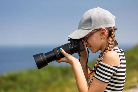 12 year old girl taking pictures with a long lens in a beautiful scenic of Irish cliffsの写真素材