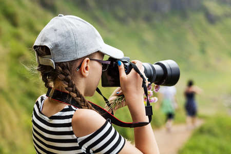 12 year old girl taking pictures with a long lens in a beautiful scenic of Irish cliffsの写真素材