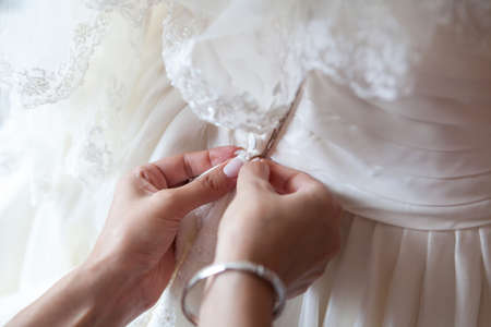 bridesmaid buttoning on corset bride's wedding dress
