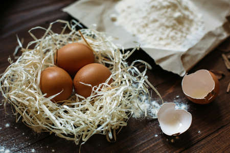 eggs and flour are on a dark wooden table in the kitchen