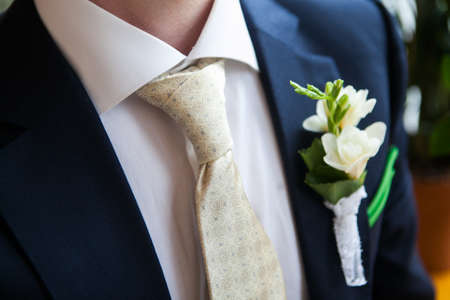 white freesia pinned to the lapel of the groomの写真素材