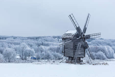 Old wooden windmill in a field covered with snow.の写真素材