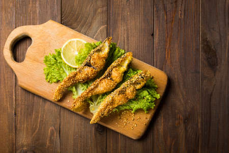 fried fish on a wooden board with lettuceの写真素材