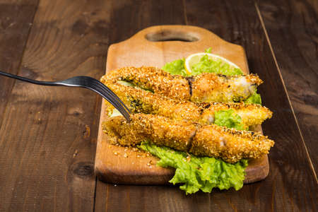 fried fish on a wooden board with lettuce close up