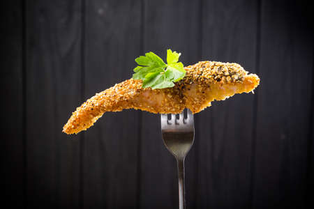 Pieces of fried Fish on a fork on a dark wooden backgroundの写真素材