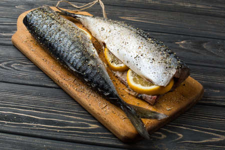 Fresh fish. Raw mackerel with salt, lemon and spices on a dark background.の写真素材