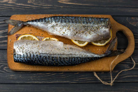 Fresh fish. Raw mackerel with salt, lemon and spices on a dark background.の写真素材