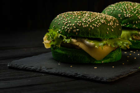 Green burger with lettuce on a black wooden backgroundの写真素材