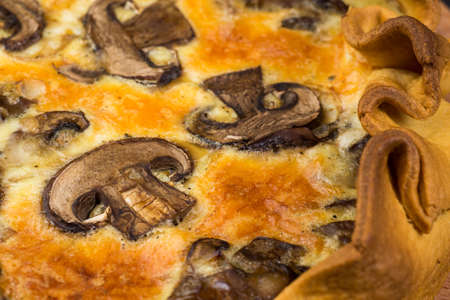 Pie with champignons and cheese on a wooden plateの写真素材