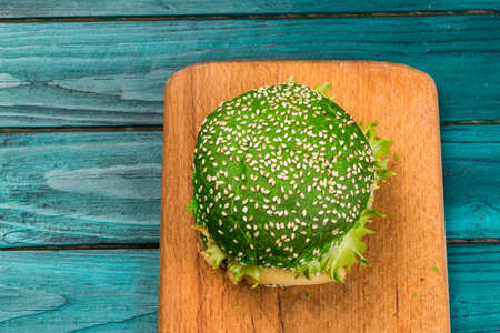 Green burger with lettuce on a wooden plank on green wooden backgroundの写真素材