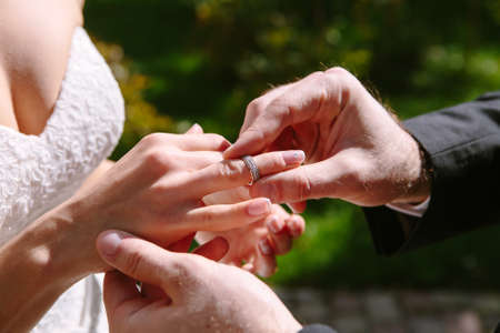 groom puts ring on the bride's handの写真素材