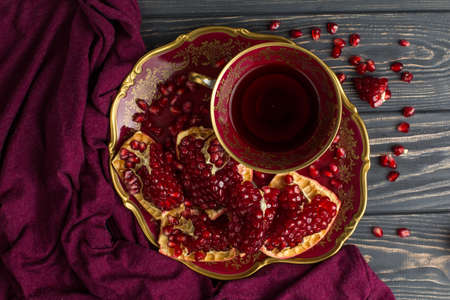 cup with red juice on a table, near a pomegranate and claret clothの写真素材