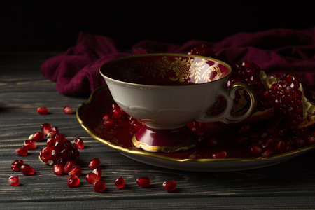cup with red juice on a table, near a pomegranate and claret clothの写真素材