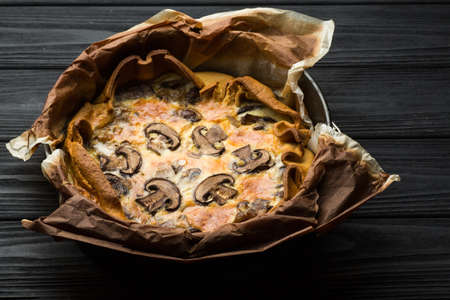 Pie with champignons and cheese on a wooden plateの写真素材