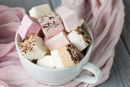 assorted marshmallow on a gray table in a cup, pink scarfの写真素材