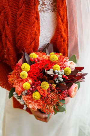 A burgundy autumn wedding bouquet in the hands of the brideの写真素材
