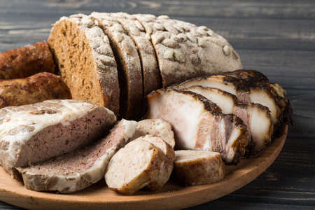 rye bread, sausage, smoked bacon on a wooden platterの写真素材