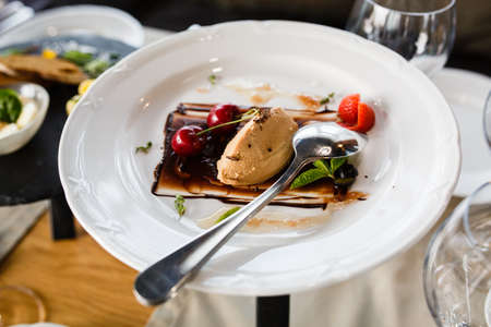 chocolate ice cream on a plate with cherries, mint and chocolate topping