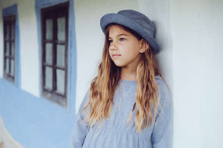 Teen girl in casual clothes and blue hat near by village houseの写真素材