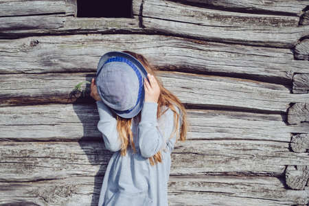 Joyful teen girl in casual clothes and blue hat posing by a wooden wall. Active lifestyle. Youth fashionの写真素材