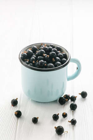 Black currant in tea cup on a white wooden table close upの写真素材