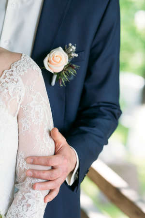 The bridegroom embraces the bride's shoulder, the buddy's jacket is boutonier