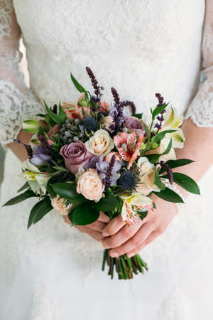 The bride is holding a bouquet of freesia, roses, pionsの写真素材