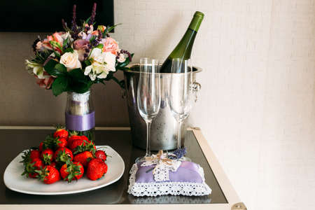 A wedding bouquet, a boutonniere, a bottle of champagne are on the table in the bride's room.の写真素材