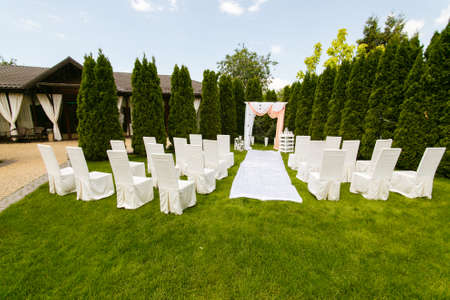Wedding arch decorated with cloth outdoors. Beautiful wedding set up. Wedding ceremony on green lawn in the garden. Part of the festive decor.の写真素材
