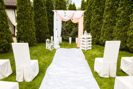 Wedding arch decorated with cloth outdoors. Beautiful wedding set up. Wedding ceremony on green lawn in the garden. Part of the festive decor.の写真素材