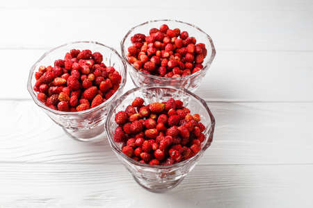 Fresh forest strawberry fruit in a glasses dish on a white table.の写真素材