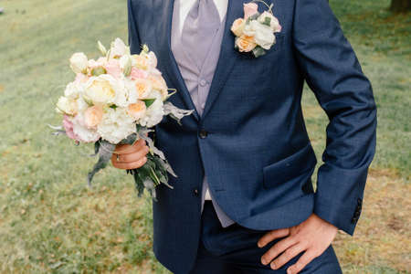 The bridegroom in a suit holds in his hands a magnificent wedding bouquet, newlyweds. Wedding concept, bridal bouquetの写真素材