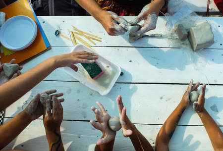 Children's hands roll the pieces of clay at the table in the lessonの写真素材