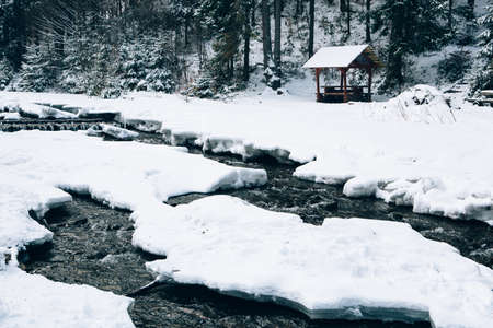 Water river and rocks covered with snow in the Carpathian Mountains near village of Pylypets