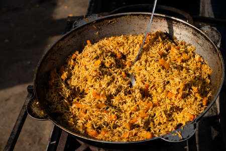 Tasty Uzbek pilaf in a cauldron in the open air at street food festivalの写真素材