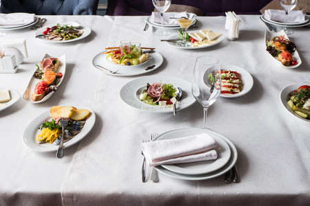Served for banquet restaurant table with dishes, snack, cutlery, wine and water glasses.