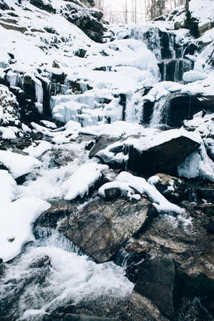 Beautiful Shypit Waterfal and rocks covered with snow. Shypit waterfall located on Pylypets River in the Carpathian Mountains, near village of Pylypets, Western Ukraine, Europe.の写真素材
