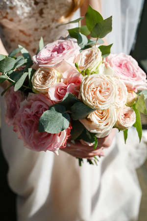 Beautiful wedding rustic bouquet with white roses. In bride handの写真素材