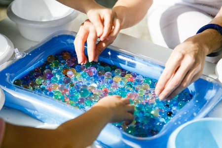 Child hands playing with colored glass ball, playing game. Child motor therapy