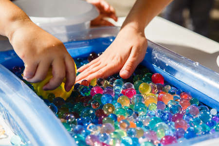 Child hands playing with colored glass ball, playing game. Child motor therapyの写真素材