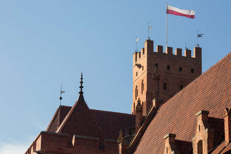 MALBORK, POLAND - OCTOBER 12, 2018: Polish flag on the tower at Malbork Castle - famous touristic...