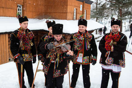 Kryvorivnia, Ukraine - January 7, 2019: Kryvorivnia, Ukraine - January 7, 2019: Violin player in national Hutsul costume plays traditional old carol song while other men sing during Christmas celebration in Ukrainian Carpathian Mountains.のeditorial素材