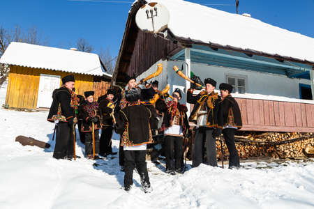 Kryvorivnia, Ukraine - January 7, 2019: Famous hutzulian Koliadnyky of Kryvorivnia singing Christmas carols and playing on traditional trembita horn. Old winter traditions of Carpathian mountains.のeditorial素材