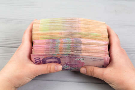 Money of Ukraine. Stack of ukrainian hryvnia banknotes in hands on wooden table. Hryvnia 500 and 200 uahの写真素材