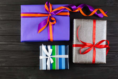 Different colors and sizes gift box with red ribbon on wooden table. Boxing day