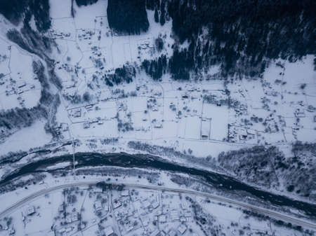 Calm and cosy fairy-tale village Kryvorivnia covered with snow in the Carpathians mountains, aerial view. Typical landscape in Hutsulshchyna National Park in Ukraine. Vacation and winter sports.の写真素材