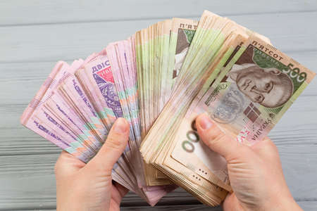 Money of Ukraine. Stack of ukrainian hryvnia banknotes in hands on wooden table. Hryvnia 500 and 200...
