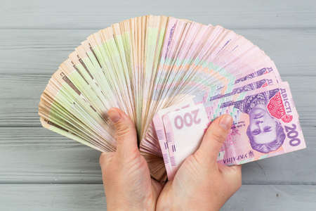 Money of Ukraine. Stack of ukrainian hryvnia banknotes in hands on wooden table. Hryvnia 500 and 200...