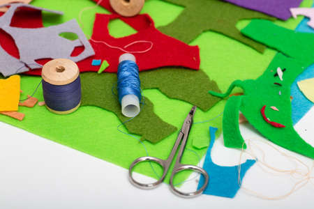 Colored felt, thread, needles and scissors on the white tableの写真素材