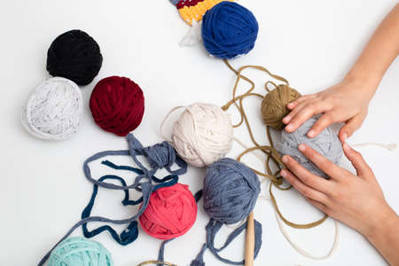 Different colored balls of thread. Yarn for knitting with child hands view frome above
